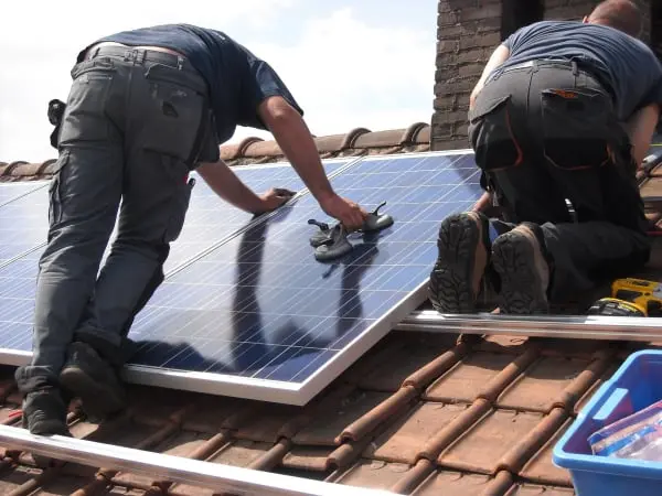Workmen installing solar panels on rooftop